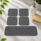 Eco-friendly rectangular grey diatomite drying coaster holding a cold beverage glass with zero condensation water rings on a wooden table.